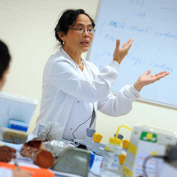 female lecturer in a white coat teaching in a laboratory at ϲϿ