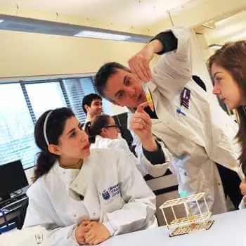 male lecturer explaining an experiment to two students in a science laboratory at ϲϿ